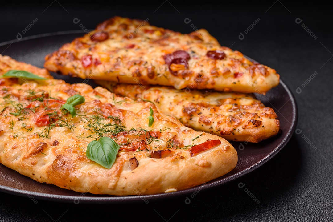 Deliciosa pizza de pão achatado fresco com queijo, tomate, salsicha, sal e especiarias sobre um fundo escuro de concreto