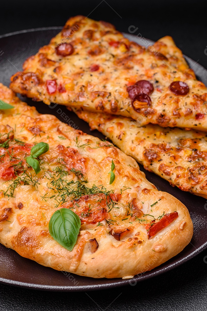 Deliciosa pizza de pão achatado fresco com queijo, tomate, salsicha, sal e especiarias sobre um fundo escuro de concreto