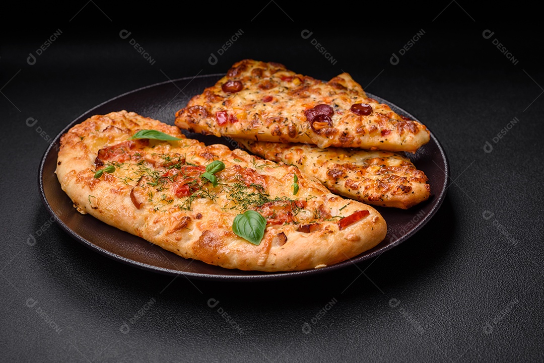 Deliciosa pizza de pão achatado fresco com queijo, tomate, salsicha, sal e especiarias sobre um fundo escuro de concreto