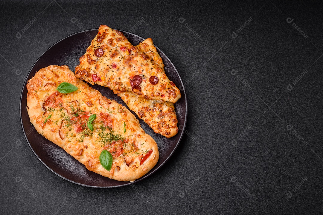 Deliciosa pizza de pão achatado fresco com queijo, tomate, salsicha, sal e especiarias sobre um fundo escuro de concreto