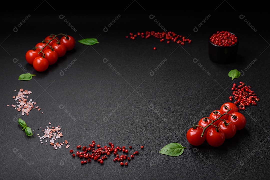 Ingredientes para cozinhar tomate cereja, sal, especiarias e ervas sobre um fundo escuro de concreto