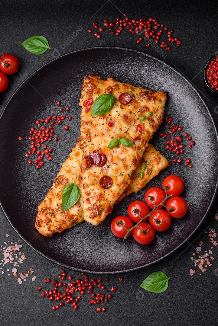 Deliciosa pizza de pão achatado fresco com queijo, tomate, salsicha, sal e especiarias sobre um fundo escuro de concreto