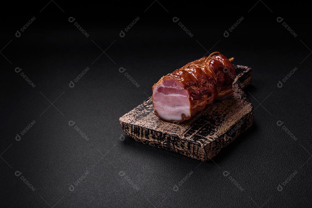 Delicioso bacon defumado com sal, especiarias e ervas sobre um fundo escuro de concreto