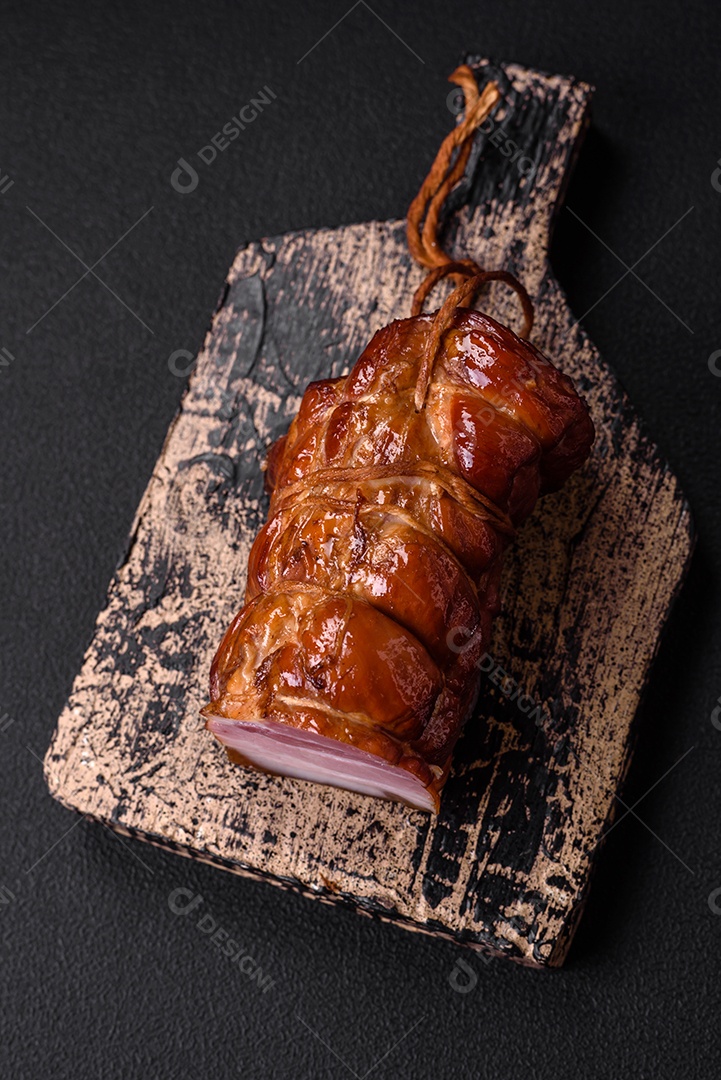 Delicioso bacon defumado com sal, especiarias e ervas sobre um fundo escuro de concreto