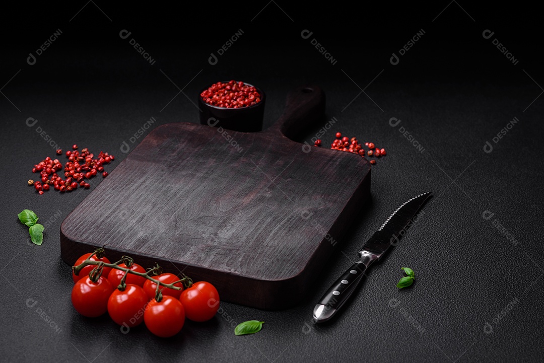 Ingredientes para cozinhar tomate cereja, sal, especiarias e ervas sobre um fundo escuro de concreto