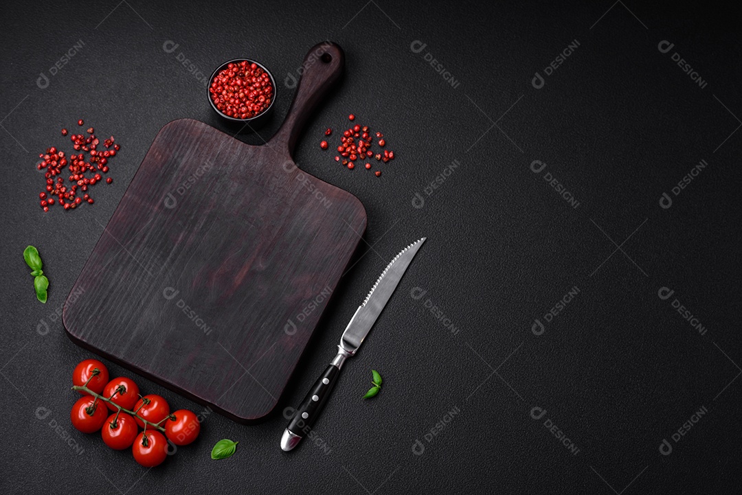 Ingredientes para cozinhar tomate cereja, sal, especiarias e ervas sobre um fundo escuro de concreto