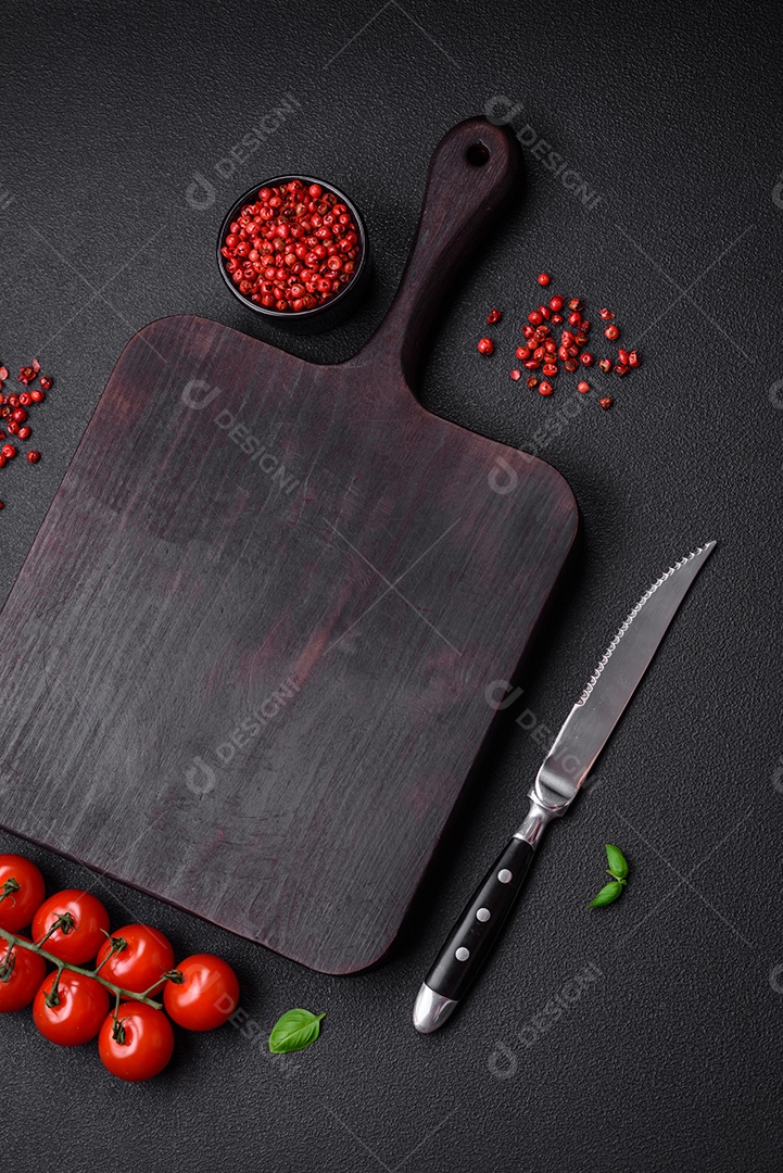 Ingredientes para cozinhar tomate cereja, sal, especiarias e ervas sobre um fundo escuro de concreto