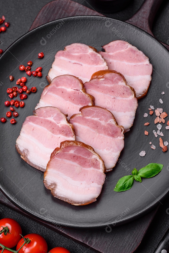 Delicioso bacon defumado com sal, especiarias e ervas sobre um fundo escuro de concreto