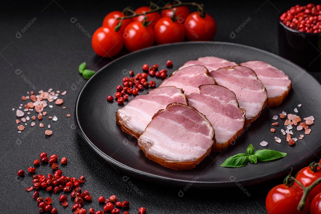 Delicioso bacon defumado com sal, especiarias e ervas sobre um fundo escuro de concreto