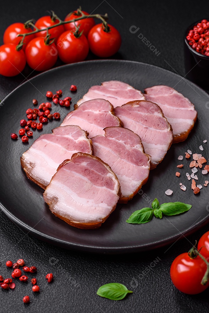 Delicioso bacon defumado com sal, especiarias e ervas sobre um fundo escuro de concreto