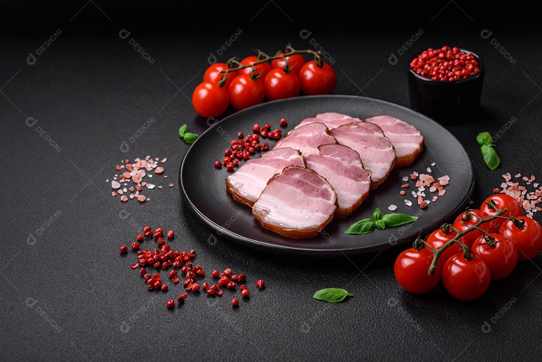 Delicioso bacon defumado com sal, especiarias e ervas sobre um fundo escuro de concreto