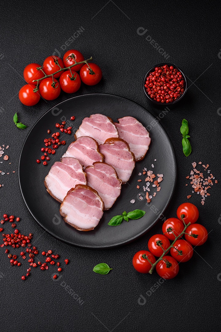 Delicioso bacon defumado com sal, especiarias e ervas sobre um fundo escuro de concreto