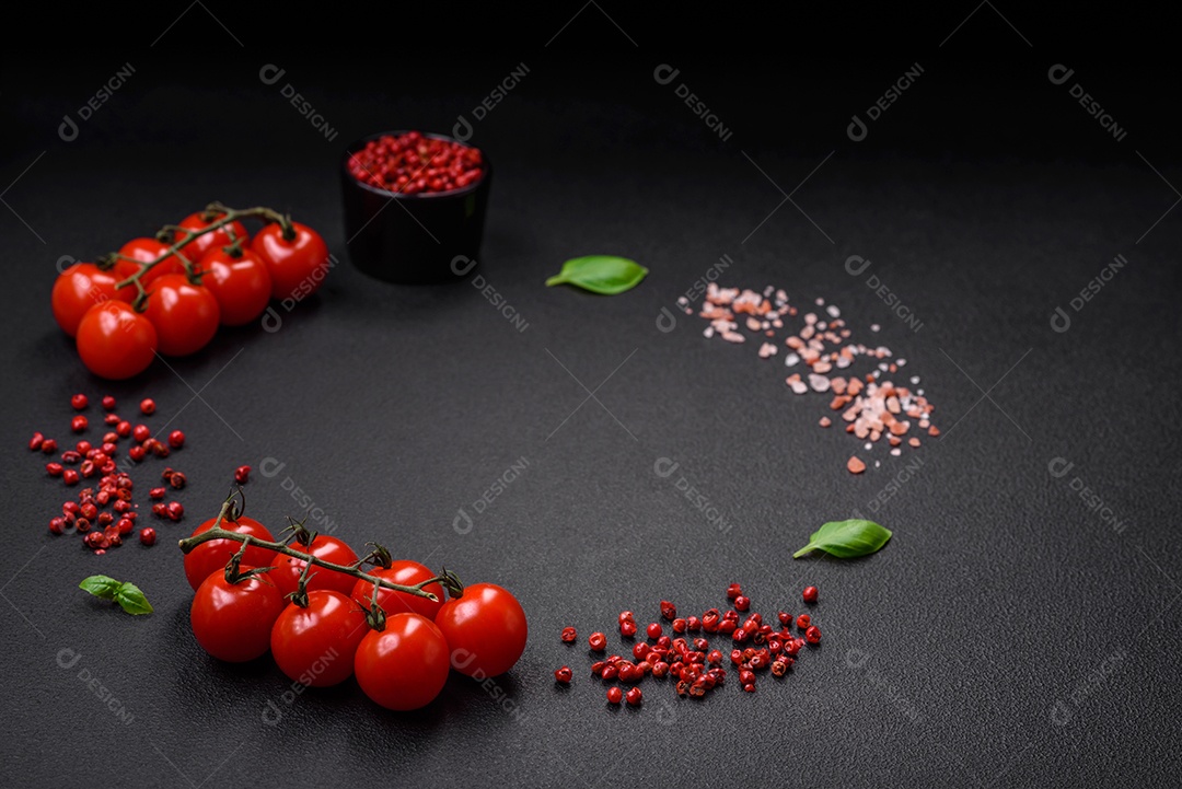 Ingredientes para cozinhar tomate cereja, sal, especiarias e ervas sobre um fundo escuro de concreto