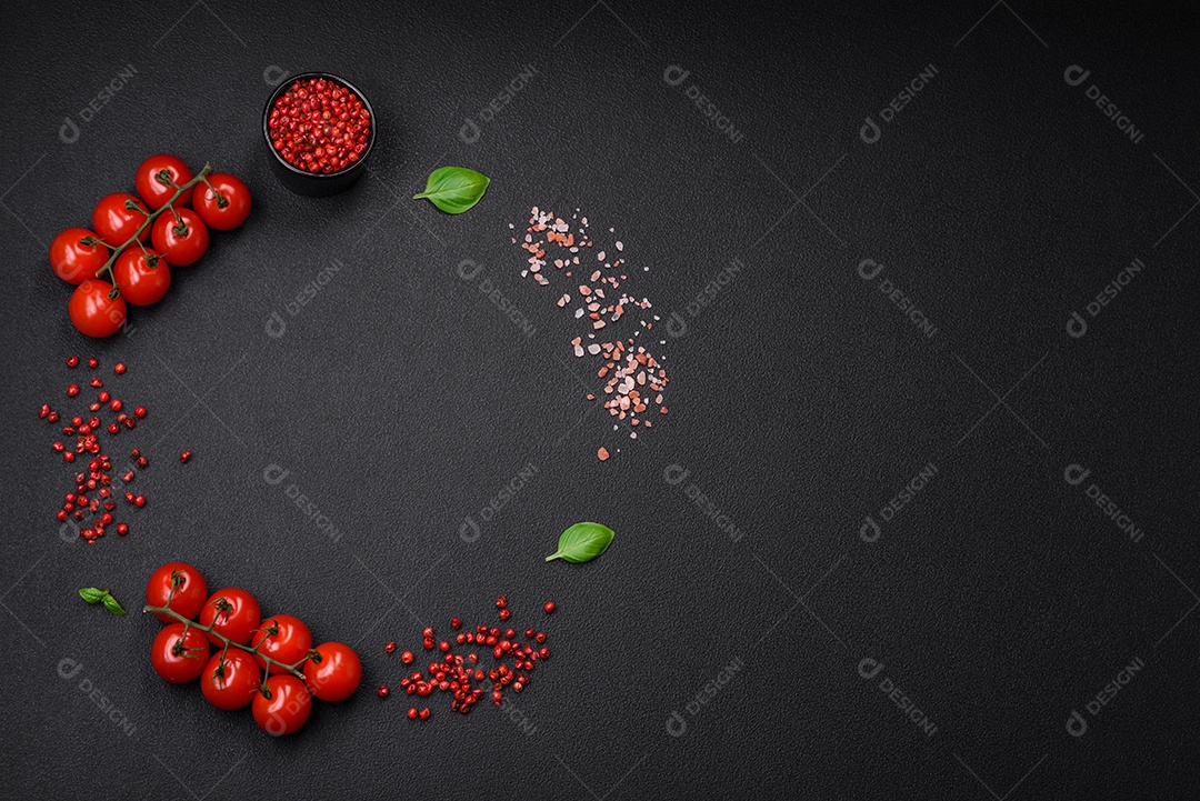 Ingredientes para cozinhar tomate cereja, sal, especiarias e ervas sobre um fundo escuro de concreto