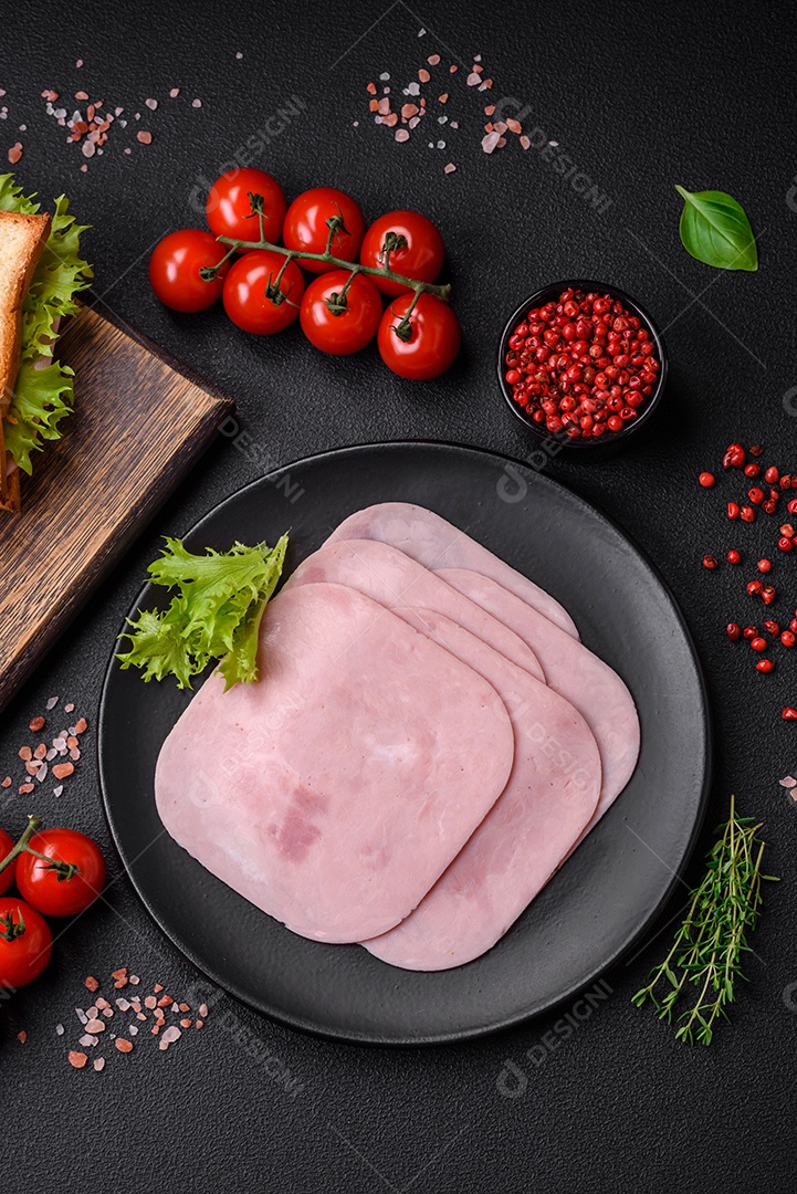 Delicioso sanduíche com torradas, presunto, tomate, queijo e alface com sal, especiarias e ervas sobre fundo escuro de concreto