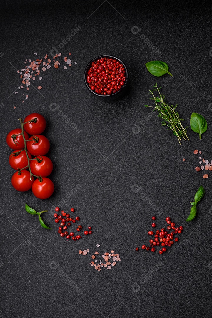 Ingredientes para cozinhar tomate cereja, sal, especiarias e ervas sobre um fundo escuro de concreto
