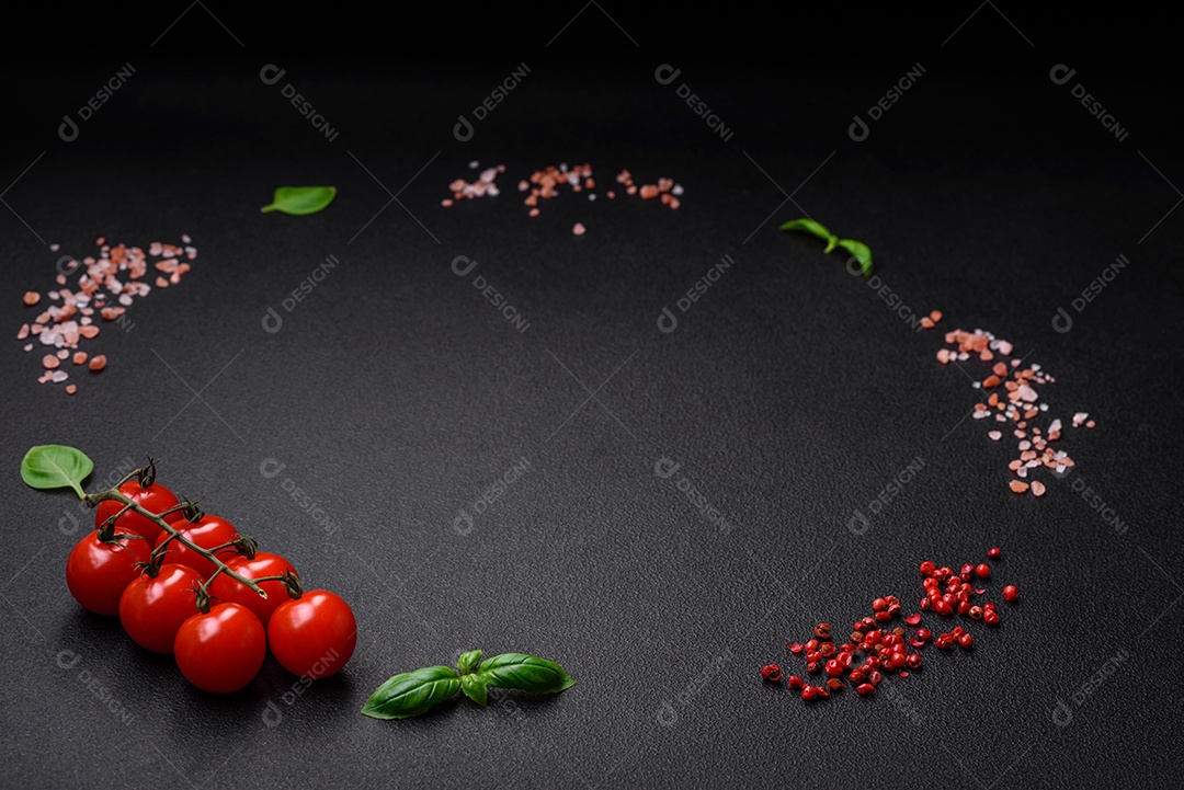 Ingredientes para cozinhar tomate cereja, sal, especiarias e ervas sobre um fundo escuro de concreto