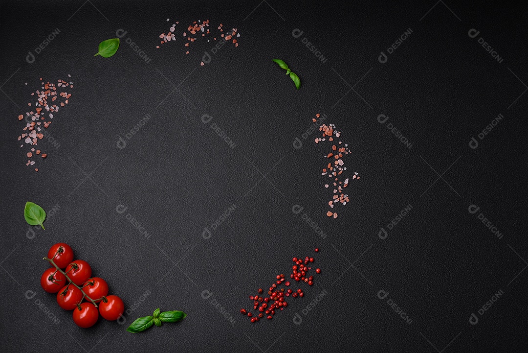Ingredientes para cozinhar tomate cereja, sal, especiarias e ervas sobre um fundo escuro de concreto