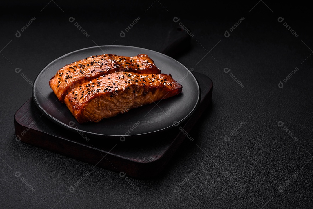 Delicioso peixe vermelho grelhado fresco com sal, especiarias e ervas sobre um fundo escuro de concreto