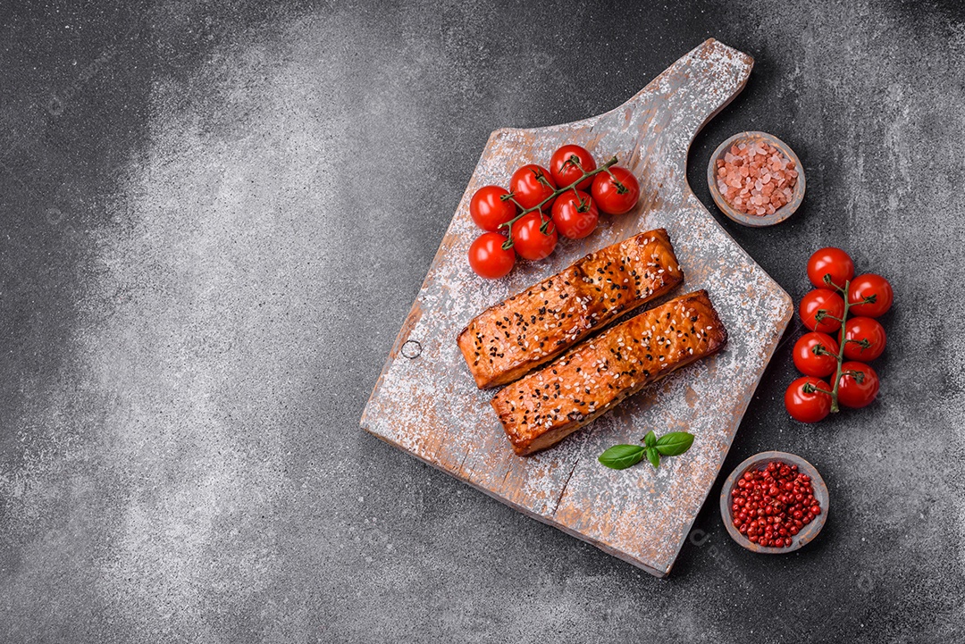Delicioso peixe vermelho grelhado fresco com sal, especiarias e ervas sobre um fundo escuro de concreto