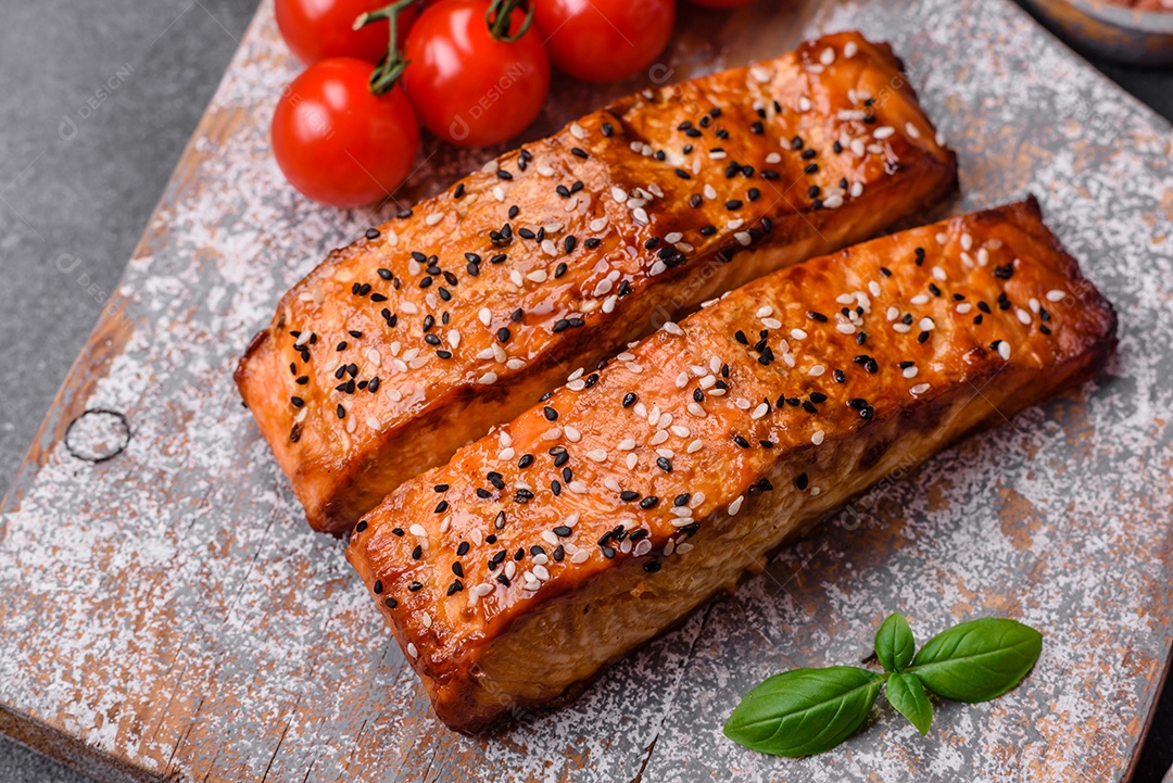 Delicioso peixe vermelho grelhado fresco com sal, especiarias e ervas sobre um fundo escuro de concreto