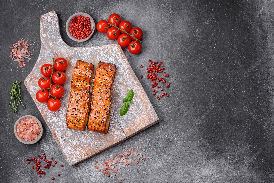 Delicioso peixe vermelho grelhado fresco com sal, especiarias e ervas sobre um fundo escuro de concreto