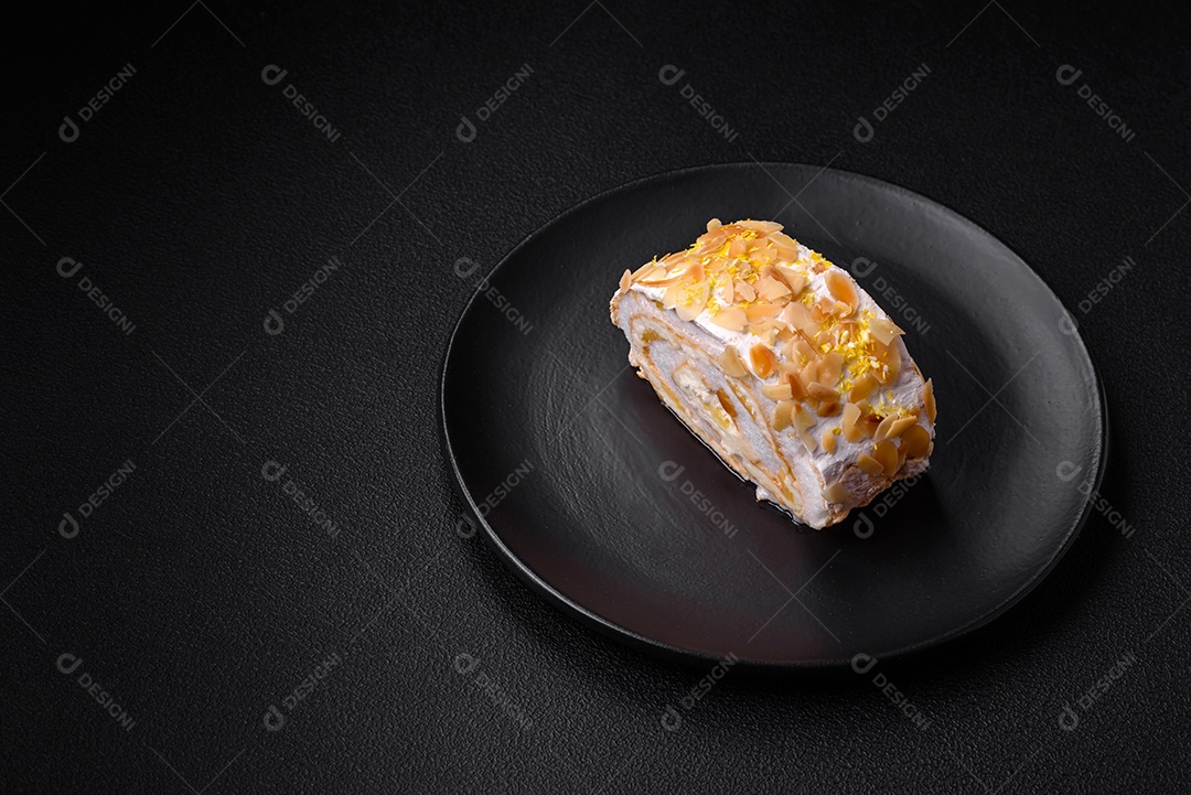 Rolo de merengue delicioso, fresco e doce com creme, lascas de amêndoa, nozes e frutas cortadas em fatias sobre um fundo escuro de concreto