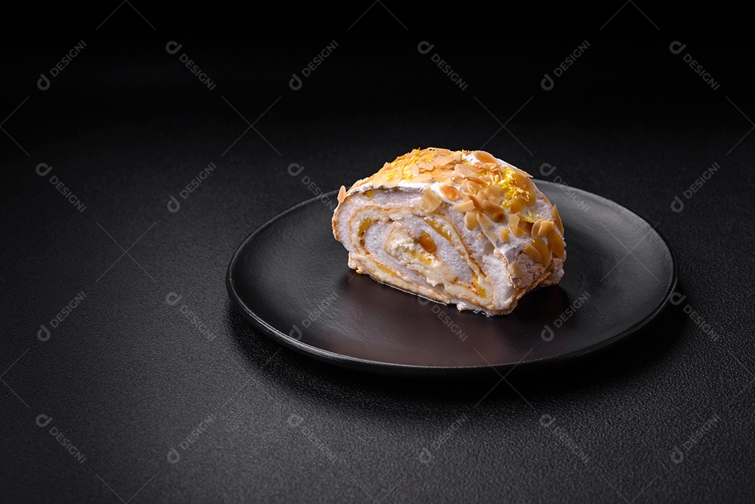 Rolo de merengue delicioso, fresco e doce com creme, lascas de amêndoa, nozes e frutas cortadas em fatias sobre um fundo escuro de concreto