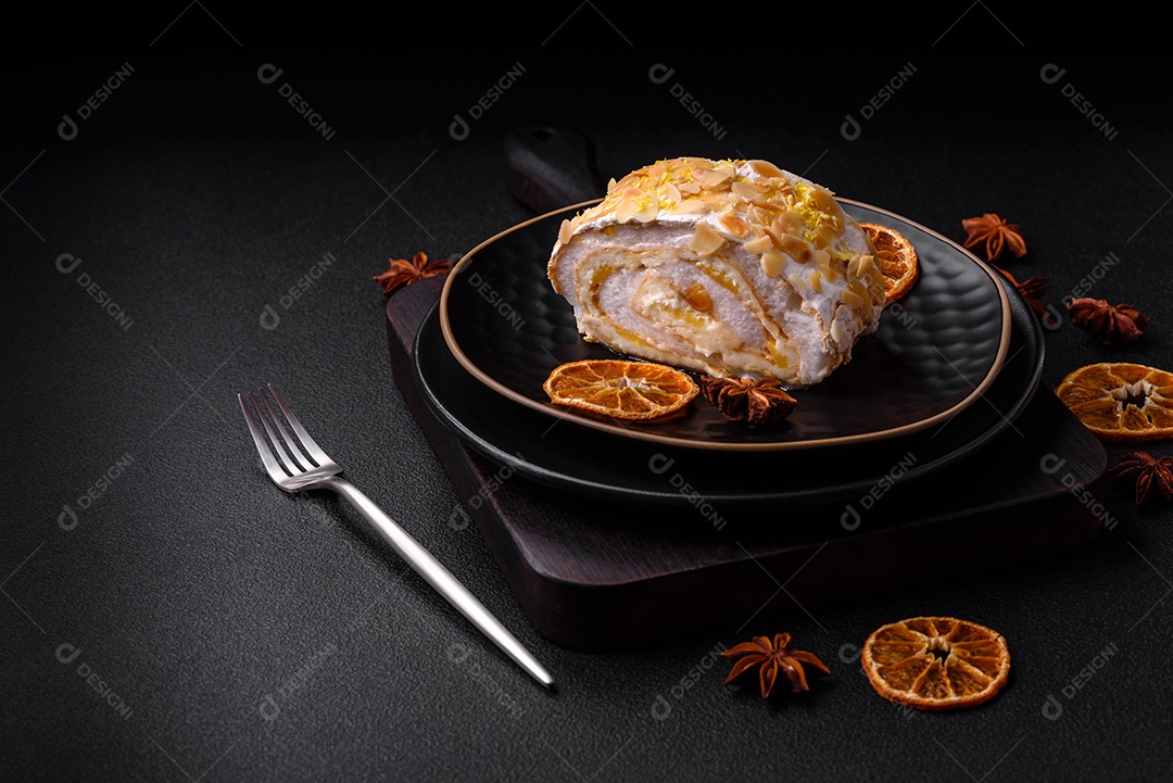Rolo de merengue delicioso, fresco e doce com creme, lascas de amêndoa, nozes e frutas cortadas em fatias sobre um fundo escuro de concreto