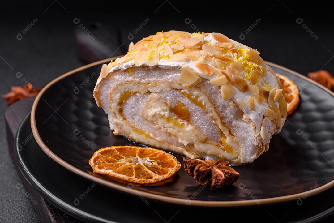 Rolo de merengue delicioso, fresco e doce com creme, lascas de amêndoa, nozes e frutas cortadas em fatias sobre um fundo escuro de concreto