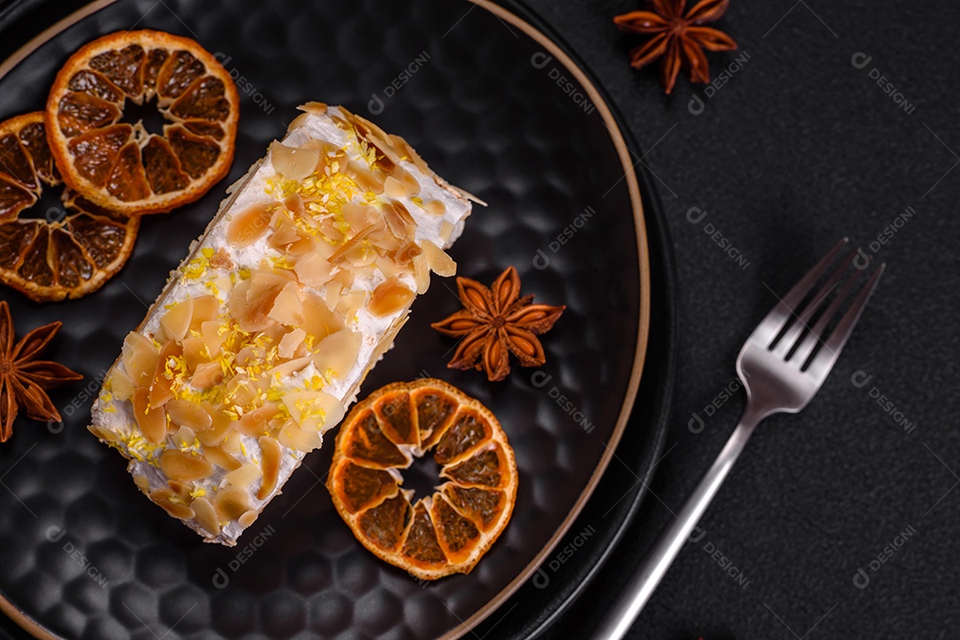 Rolo de merengue delicioso, fresco e doce com creme, lascas de amêndoa, nozes e frutas cortadas em fatias sobre um fundo escuro de concreto