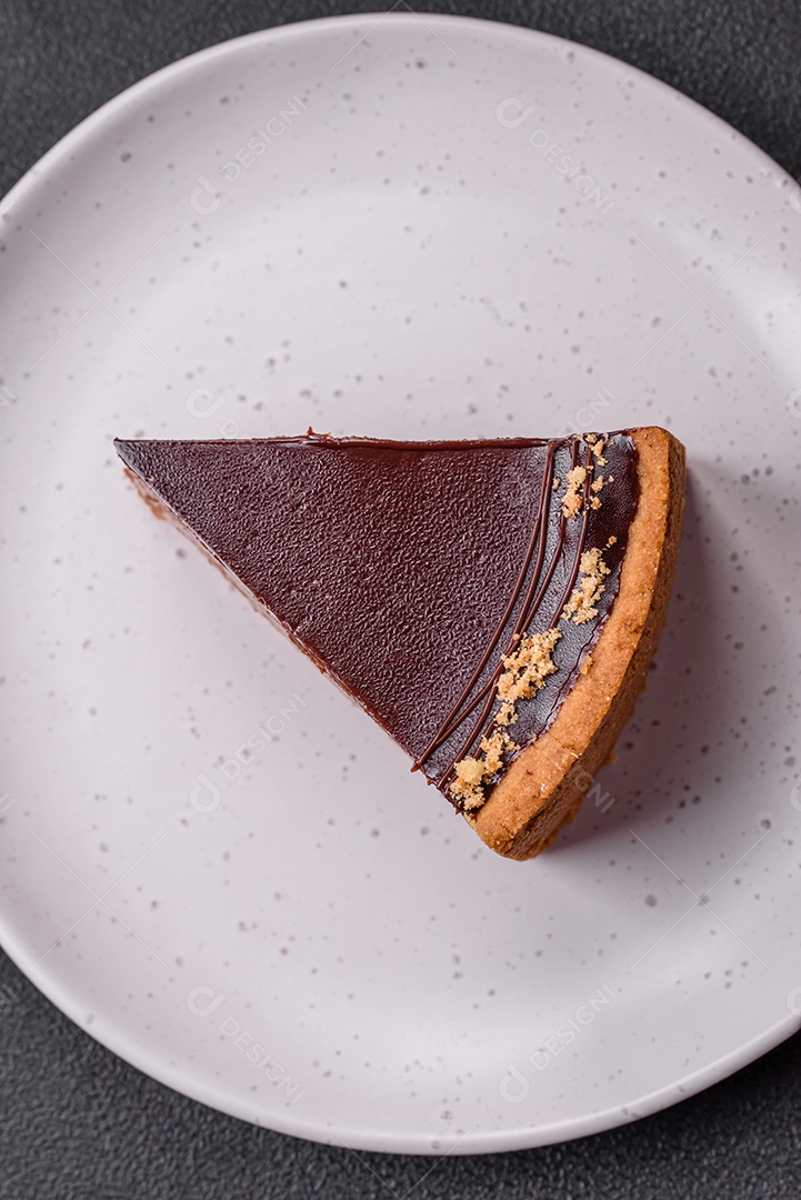 Rolo de merengue delicioso, fresco e doce com creme, lascas de amêndoa, nozes e frutas cortadas em fatias sobre um fundo escuro de concreto