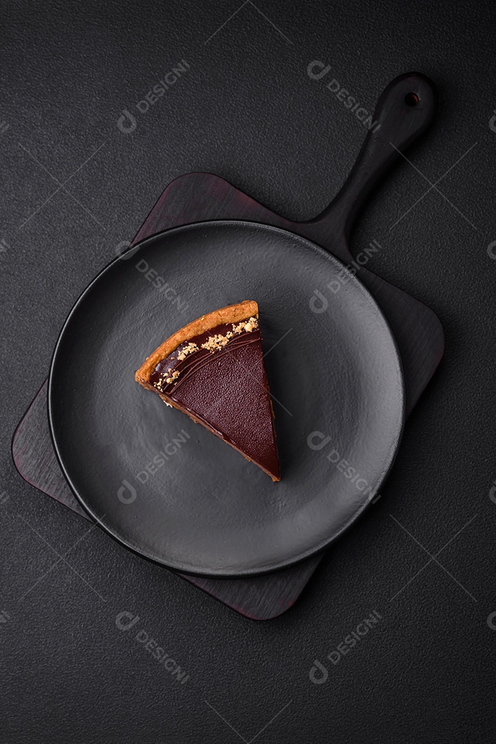 Rolo de merengue delicioso, fresco e doce com creme, lascas de amêndoa, nozes e frutas cortadas em fatias sobre um fundo escuro de concreto