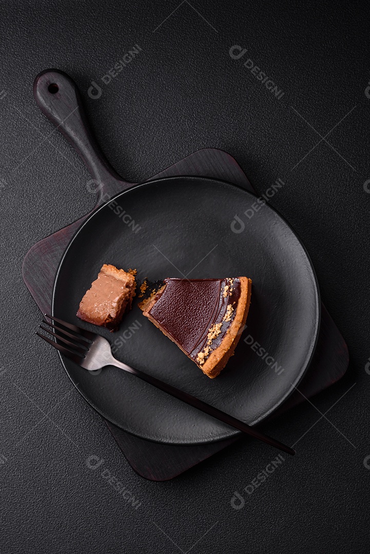 Rolo de merengue delicioso, fresco e doce com creme, lascas de amêndoa, nozes e frutas cortadas em fatias sobre um fundo escuro de concreto