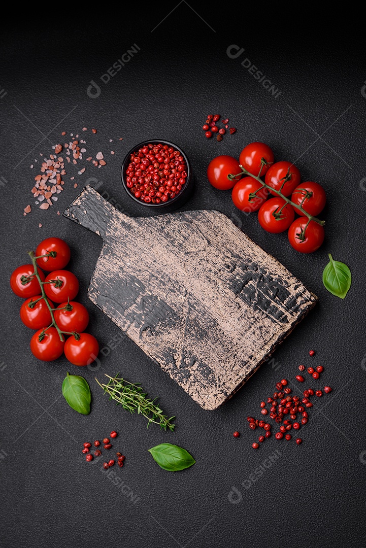 Deliciosos tomates cereja frescos nos galhos como ingrediente para cozinhar um prato vegetariano sobre um fundo escuro de concreto