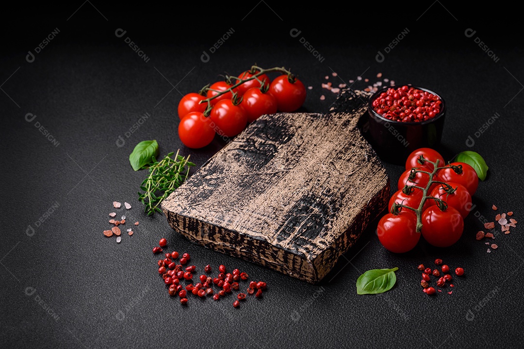 Deliciosos tomates cereja frescos nos galhos como ingrediente para cozinhar um prato vegetariano sobre um fundo escuro de concreto