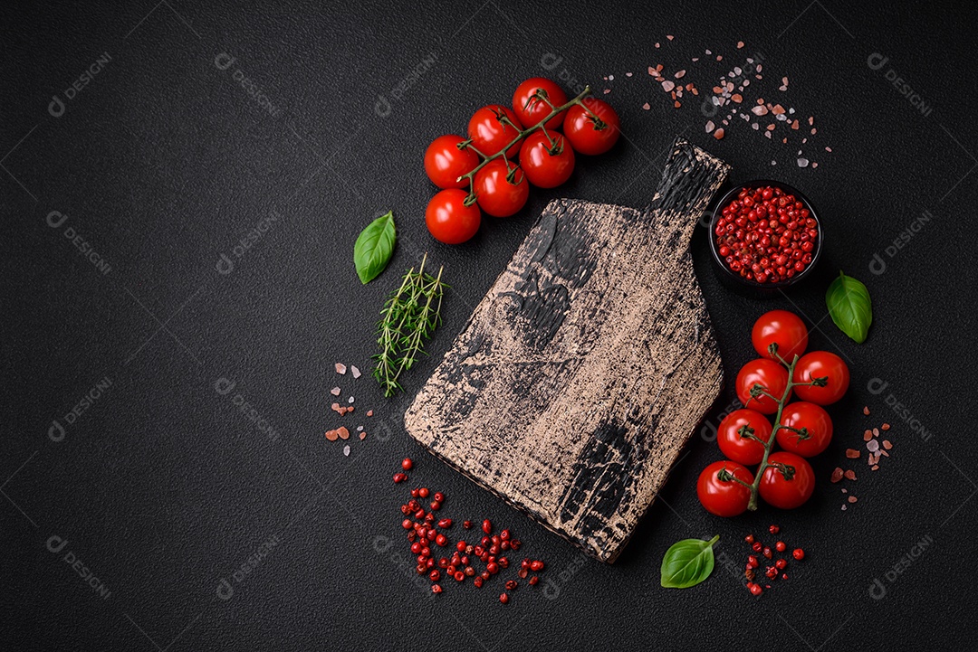 Deliciosos tomates cereja frescos nos galhos como ingrediente para cozinhar um prato vegetariano sobre um fundo escuro de concreto