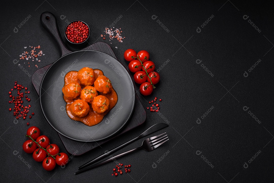 Deliciosas almôndegas frescas em molho de tomate com sal, especiarias e ervas sobre um fundo escuro de concreto