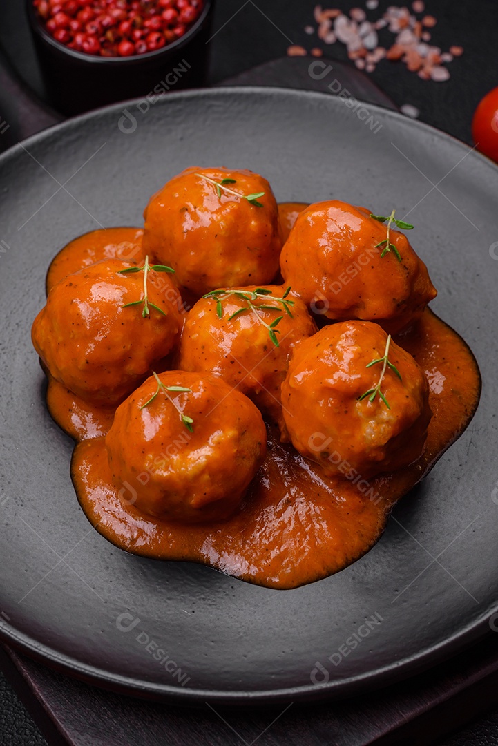 Deliciosas almôndegas frescas e massas em molho de tomate com sal, especiarias e ervas sobre um fundo escuro de concreto