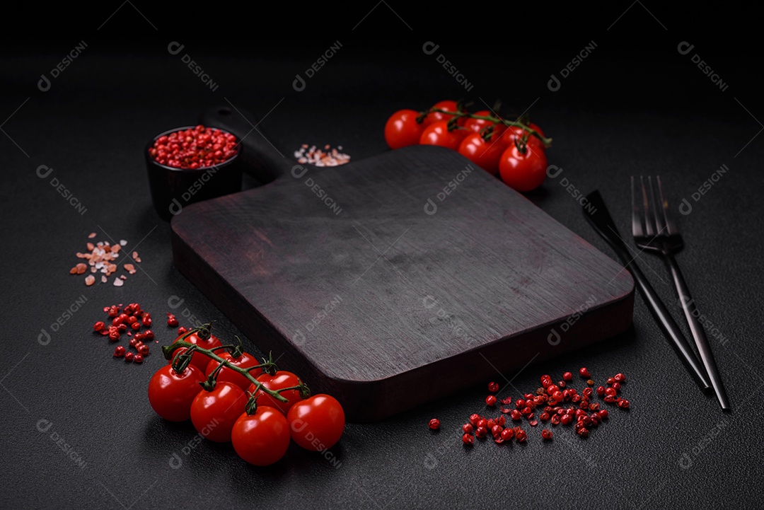 Deliciosos tomates cereja frescos nos galhos como ingrediente para cozinhar um prato vegetariano sobre um fundo escuro de concreto