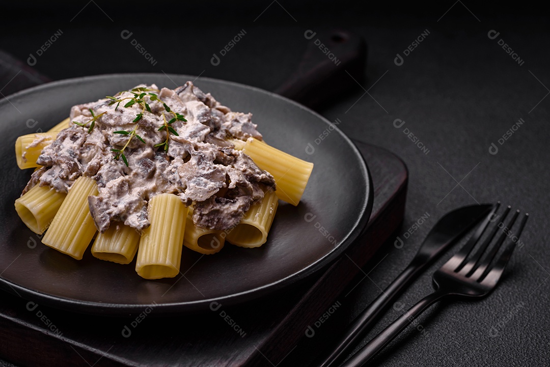 Deliciosa massa fresca com cogumelos champignon em molho cremoso com sal, especiarias e ervas sobre fundo escuro de concreto