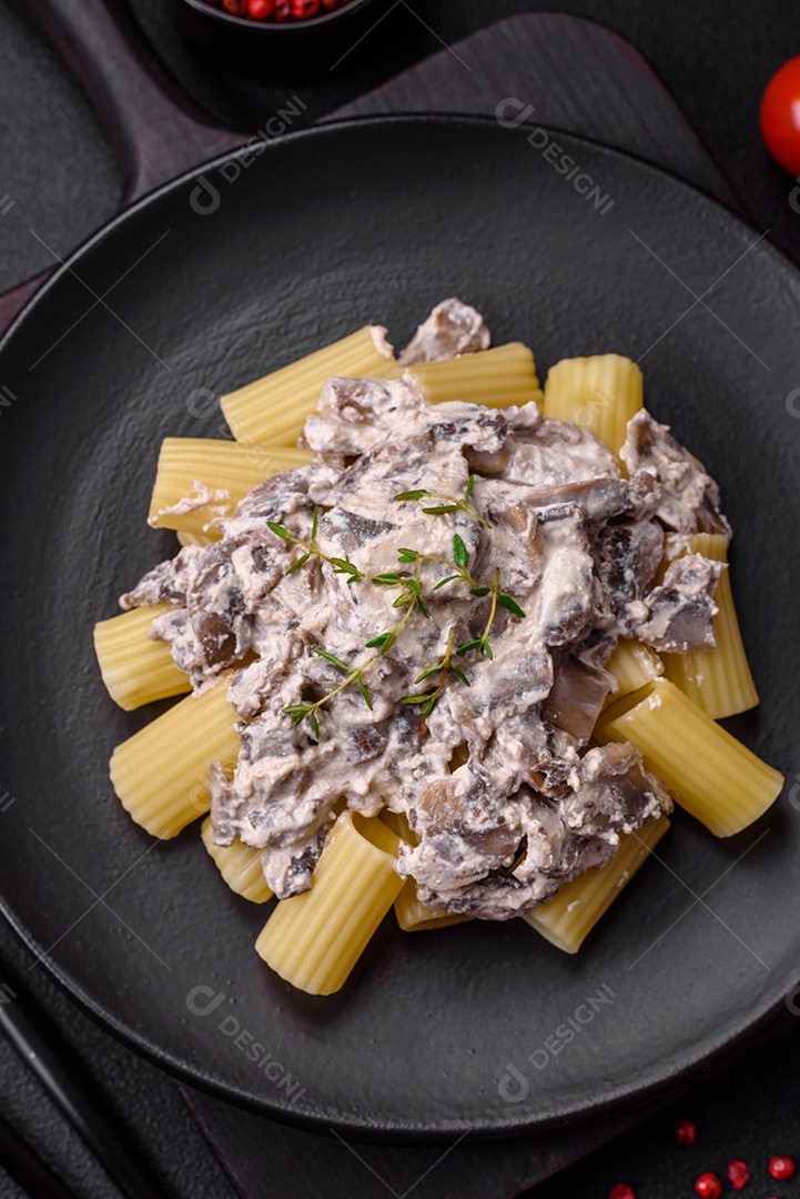 Deliciosa massa fresca com cogumelos champignon em molho cremoso com sal, especiarias e ervas sobre fundo escuro de concreto