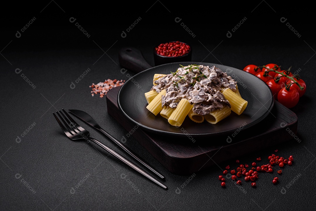 Deliciosa massa fresca com cogumelos champignon em molho cremoso com sal, especiarias e ervas sobre fundo escuro de concreto