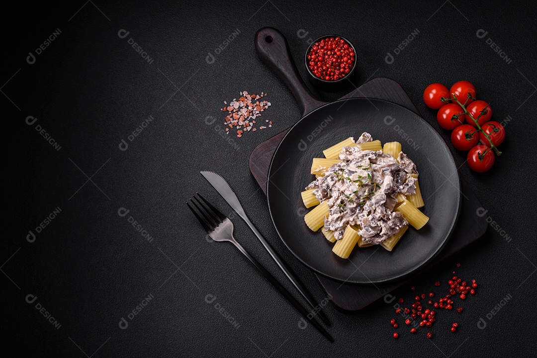 Deliciosa massa fresca com cogumelos champignon em molho cremoso com sal, especiarias e ervas sobre fundo escuro de concreto