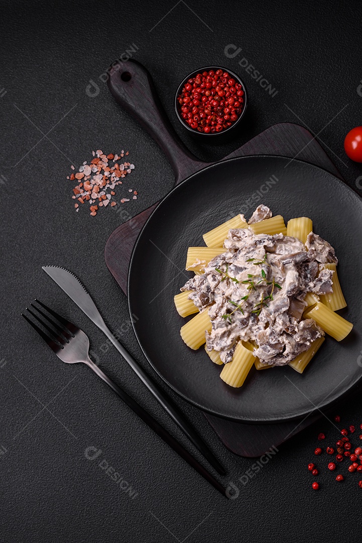 Deliciosa massa fresca com cogumelos champignon em molho cremoso com sal, especiarias e ervas sobre fundo escuro de concreto