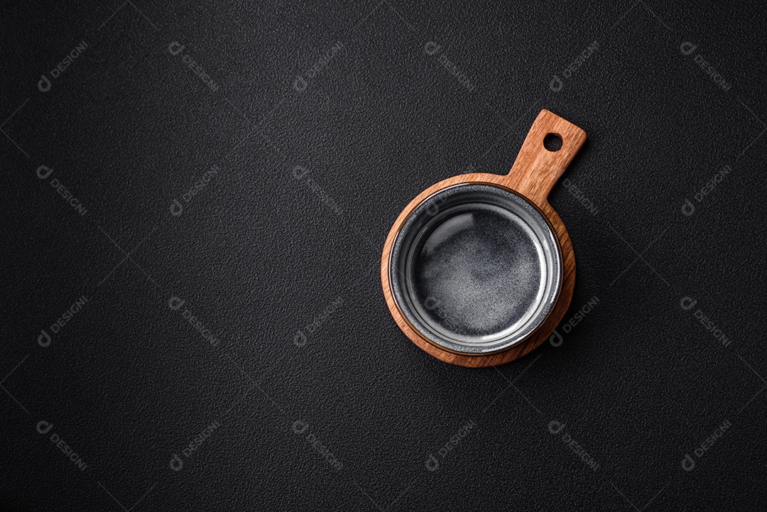 Tigela de cerâmica redonda vazia sobre uma tábua de madeira de cor marrom sobre um fundo de concreto texturizado escuro