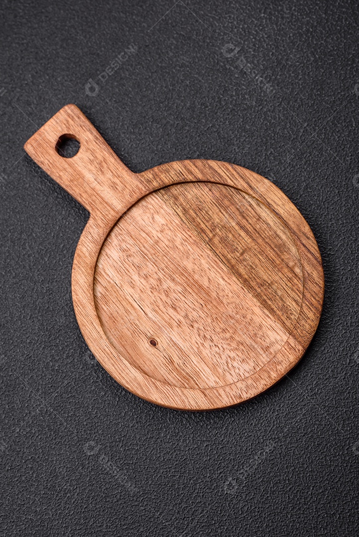 Tábua de corte de madeira de cozinha redonda vazia na cor marrom sobre um fundo de concreto texturizado escuro