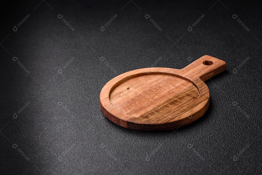 Tábua de corte de madeira de cozinha redonda vazia na cor marrom sobre um fundo de concreto texturizado escuro