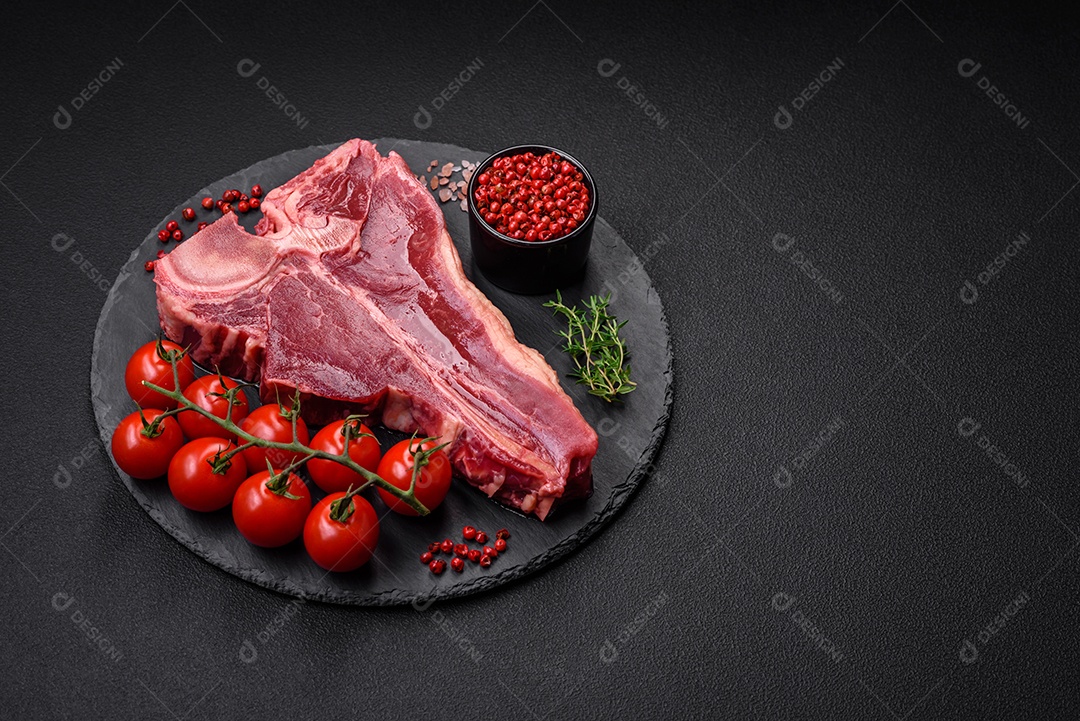 Bife de carne crua e suculenta com sal, especiarias e ervas sobre um fundo escuro de concreto