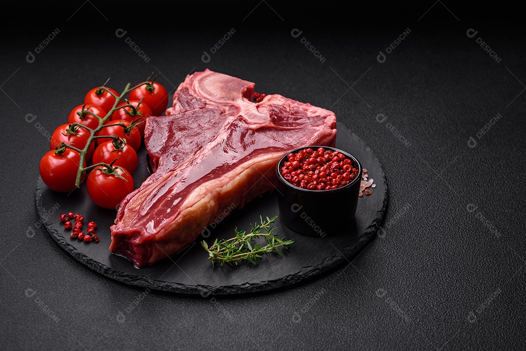 Bife de carne crua e suculenta com sal, especiarias e ervas sobre um fundo escuro de concreto
